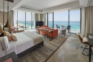 modernes Schlafzimmer der Sea Front Suite mit eckbalkon und ausblick auf das meer in warmen farben und grosser fensterfront direkt vor dem bett im Mandarin oriental jumeira in dubai