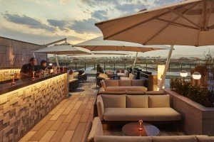 moderne und gemütliche terrasse mit bar und lounge möbeln im warmen licht des sonnenuntergangs