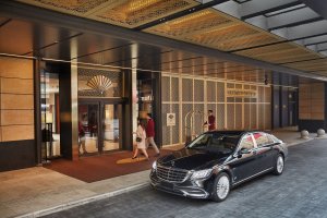 eingangsbereich des luxushotels mandarin oriental in peking mit merzedes limusine vor dem großen logo des hotels das über dem eingang trohnt