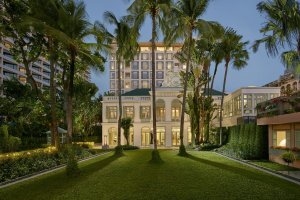 Außenansicht des Authors Flügel mit saftigem Rasen im Vordergrund Palmen und der hellen Luxus-Fassade mit Rundbögen