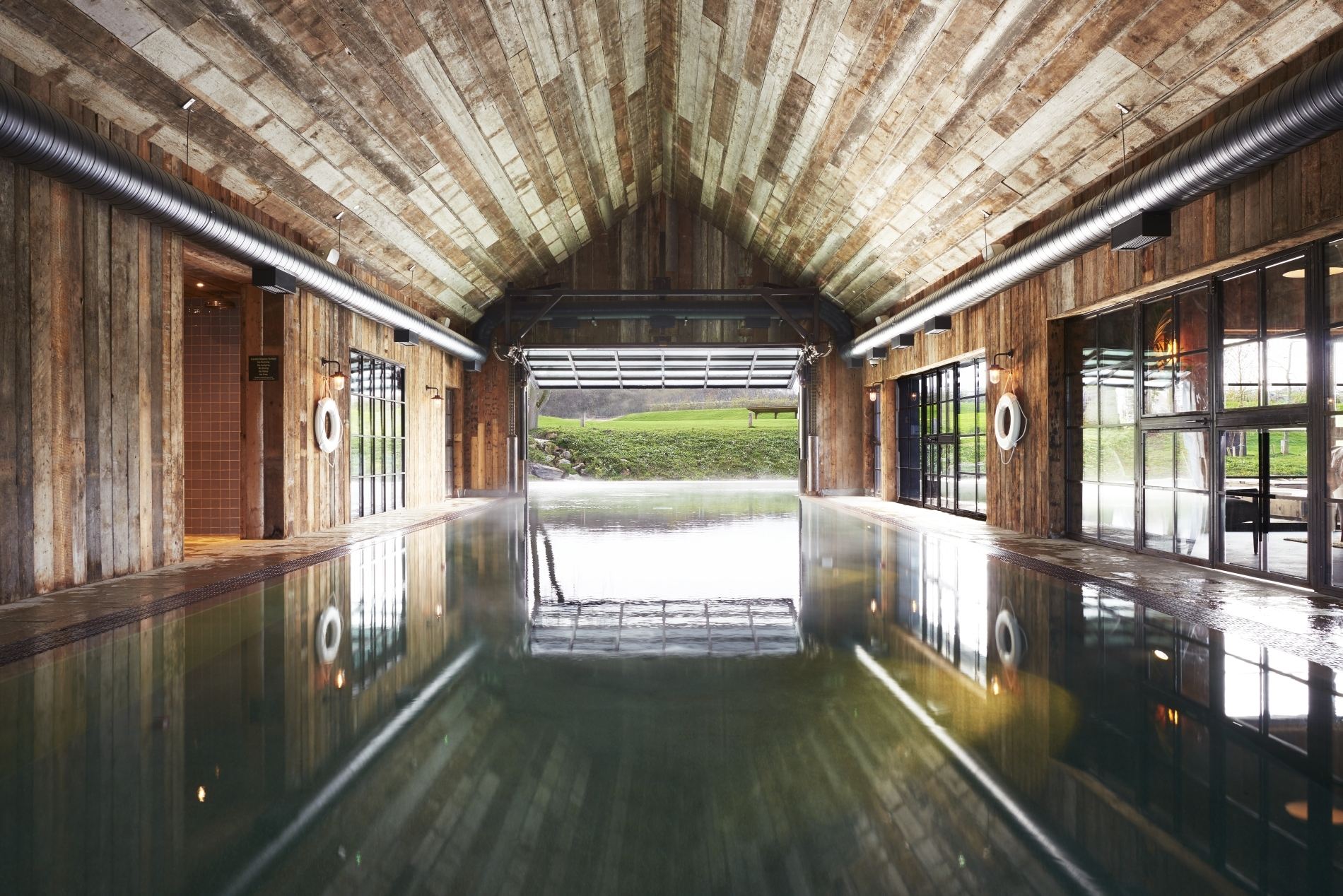 großer innen pool im bootshaus mit holzdecke und blick nach draußen im exklusiven soho farmhouse in england Oxfordshire