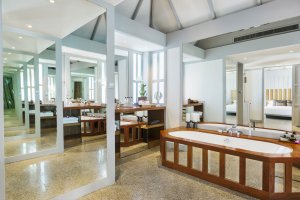 helles badezimmer im luxushotel the surin mit großen fenstern und blick in die natur thailands