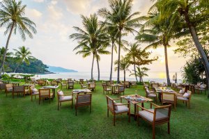 saftig grüne wiese auf der gedeckte tische des beach restaurants im luxushotel the surin phuket stehen mit blick auf das meer
