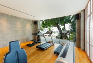fitness studio mit laufband und anderen sportgeräten im luxus resort in thailand phuket mit blick in die herrliche gartenanlage des hotels