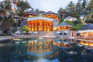 luxuspool bei nacht mit beleuchtetem hotel auf phuket und umgeben von palmen und lampen