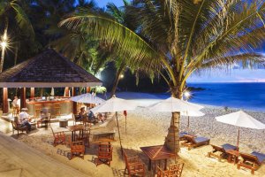 strandrestaurant bei nacht direkt am feinen sandstrand mit blick zum meer im luxus resort the surin phuket mit gedeckten tischen zum dinner