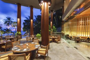 modernes und helle terrasse des restaurants im luxus hotel the surin phuket mit gedeckten tischen zum dinner und blick auf den strand von thailand