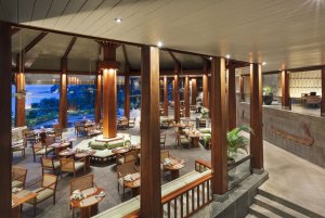 großes restaurant auf zwei etagen mit offener teppe und blick in den garten im luxushotel the surin phuket