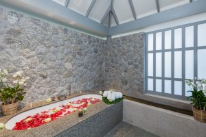 stein badewanne mit blütenblättern geschmückt im spa bereich des luxus hotel the surin phuket in thailand für entspannende momente im traumurlaub
