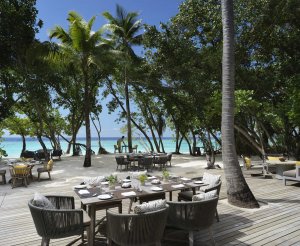 wunderschoene terrasse mit gemuehtlichen sitzmoebeln unter palmen am weißen sandstrand der malediven