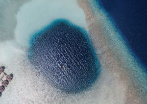 blick auf den indischen ozean aus der luft auf ein großes blaues loch inmitten der riffe vor dem vakkaru