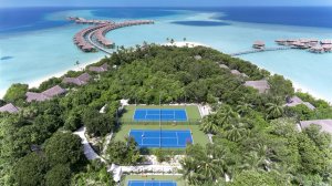 blick aus der luft auf das outdoor sport areal mit sportplätzen inmitten von palmen auf der kleinen malediven insel und weißem sandstrand am indischen ozean im hintergrund