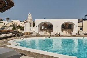 schöner pool mit gemütlichen sitzmöglichkeiten und weißen häusern im hintergrund direkt an der bar des hotels