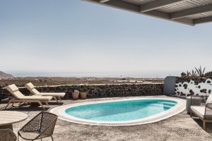 runder pool auf der stein terrasse der plympian villa im vedema resort mit zwei bequemen sonnenliegen und weitem blick in die landschaft auf santorini
