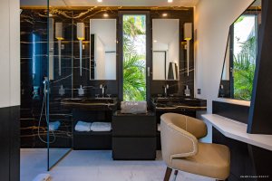 luxuriöses badezimmer in weiß und schwarztönen in der privaten luxusvilla neo auf saint barth mit großer dusche und doppelwaschbecken