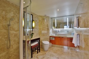 großes badezimmer mit hellbraunen marmor an den wenden und großer runden dusche in der ecke an bord des luxus schiffes