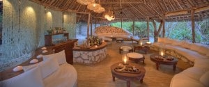 sehr gemütlicher Barbereich der andBeyond Mnemba Island Lodge auf Sansibar mit natürlichen Steinsofas kleinen Tischen und viel Holz schafft eine angenehme Stimmung