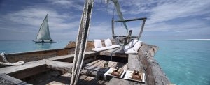 Segelboot aus Holz auf dem türkisfarbenen Meer bei Mnemba Island das mit weißen Sitzecken zum träumen und genießen einlädt