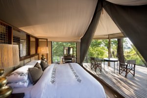 Blick in Suite 10 und das große Bett mit blick auf die Natur Afrikas im andBeyond Nxabega Okavango Tented Camp in ihrem Luxusurlaub Botswana