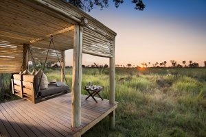 Ausblick auf der Terrasse der Tented Suite 4 in die Wildnis und den Sonnenuntergang in der weiten Natur in ihrem Luxusurlaub im andBeyond Nxabega Okavango Tented Camp