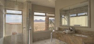 Bad mit großen Fenstern nach draußen in die Wüste Afrikas für den perfekten Namibia Luxus Urlaub fernab der Zivilisation