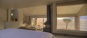großes Bett und Blick nach draußen auf die Terrasse in Zimmer 5 in der Sossusvlei Desert Lodge für den perfekten Namibia Luxus Urlaub