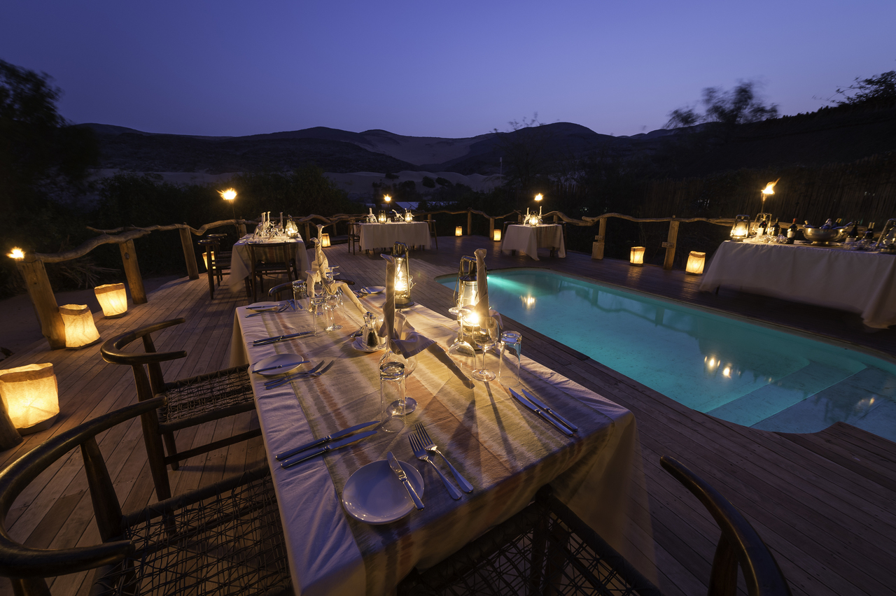 romantisches dinner am pool der serra cafema safari lodge inmitten der wunderschoenen natur afrikas bei sonnenuntergang