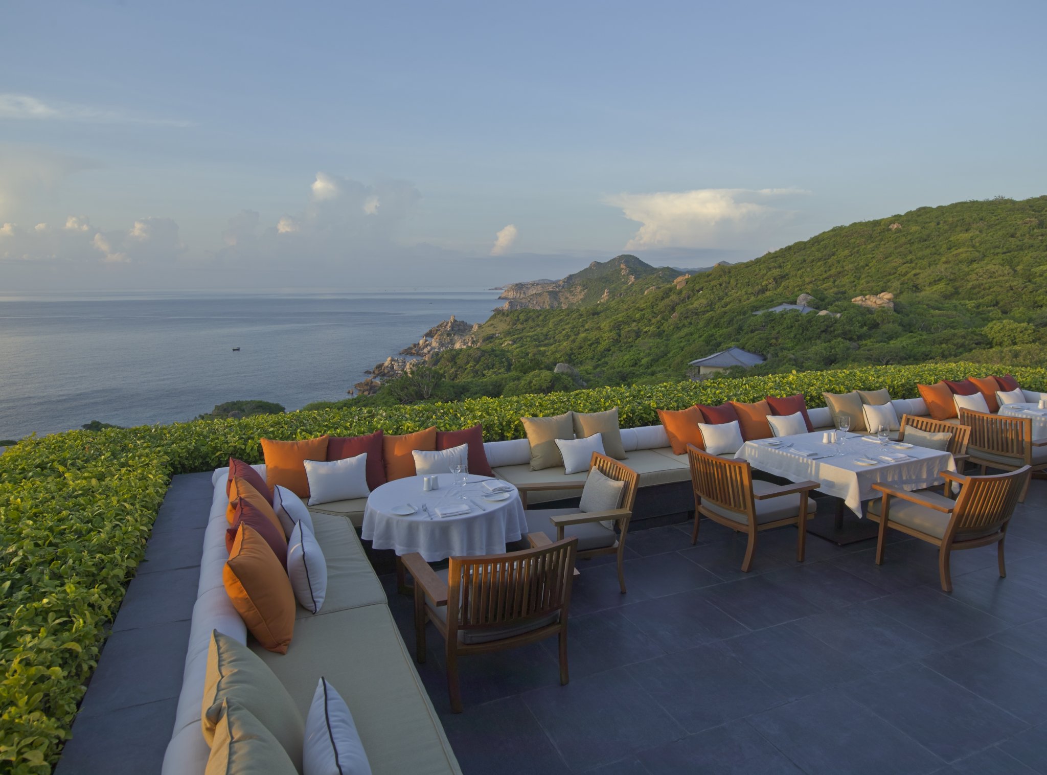 große sitzecke auf der terrasse des luxushotels amanoi mit blick in die weite grüne landschaft und das meer
