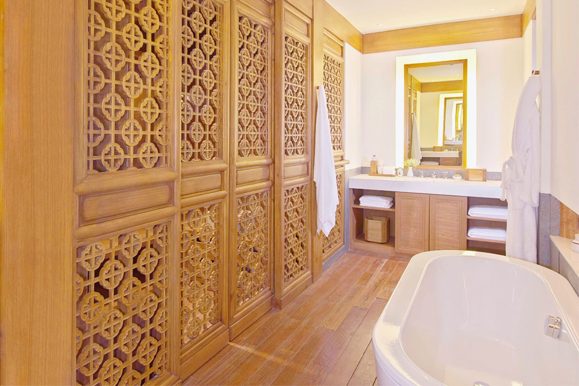 großes und helles bad im amandayan luxushotels mit großer freistehender wanne und holzvertäfeltem schrank vor dem hellen spiegel und großem waschbecken